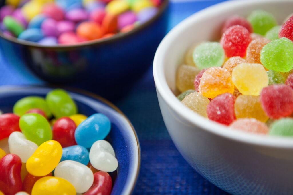 Vibrant assortment of colorful jelly beans and sugar-coated gumdrops in decorative bowls. Perfect for sweet-themed designs.